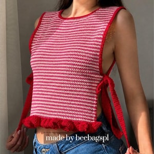 May include: A red and white striped crochet top with a round neckline and a ruffled hem. The top has red ties on the sides and is sleeveless. The text "made by beebagspl" is visible.