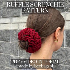 以下が含まれることがあります： フリルのある赤いクロシェのシュシュ。シュシュは女性の髪につけられています。画像には「RUFFLE SCRUNCHIE PATTERN PDF + VIDEO TUTORIAL made by beebagspl」というテキストが含まれています。