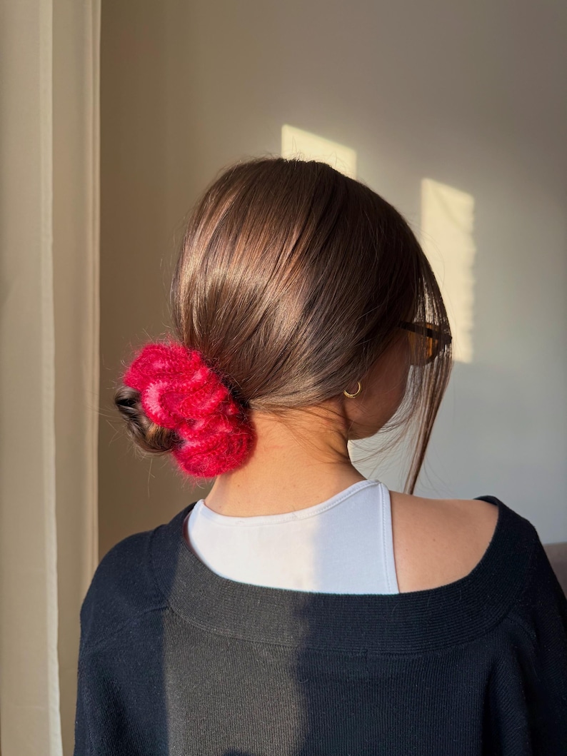 May include: A bright red and pink fluffy hair claw clip. The clip is made of a soft, textured material and is styled in the hair. The hair accessory is a stylish addition to any hairstyle.