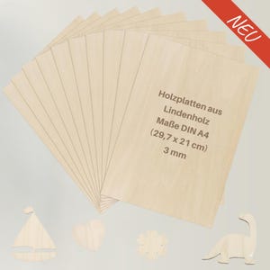 Op de afbeelding: Een stapel lichtgekleurde houten A4-vellen (29,7 cm x 21 cm) met Duitse tekst. De tekst luidt "Holzplatten aus Lindenholz" en "3 mm". De afbeelding bevat ook houten uitsparingen van een zeilboot, hart, bloem en dinosaurus.