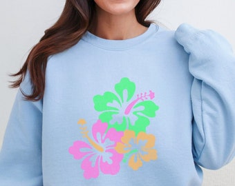 May include: A light blue sweatshirt with a colorful hibiscus flower print. The flowers are pink, green, and orange.