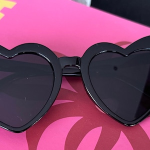 May include: Black heart-shaped sunglasses with a thick frame.