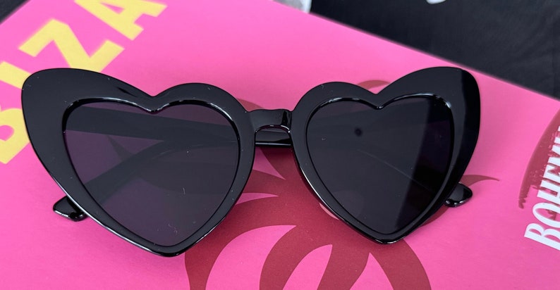 May include: Black heart-shaped sunglasses with a thick frame.