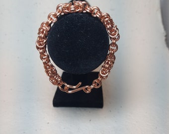 May include: A copper chain bracelet with a clasp closure. The bracelet is made of small, interconnected rings.