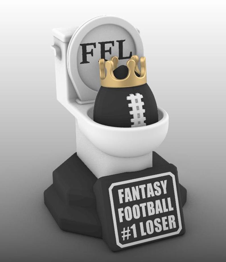 Puede incluir: Un trofeo novedoso que presenta un bal&oacute;n de f&uacute;tbol negro con una corona dorada dentro de un inodoro blanco. El inodoro tiene las letras "FFL" en la tapa. Un letrero negro en la base dice "FANTASY FOOTBALL #1 LOSER".