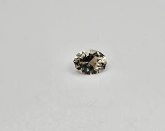 May include: A light brown oval-shaped gemstone with a faceted cut.
