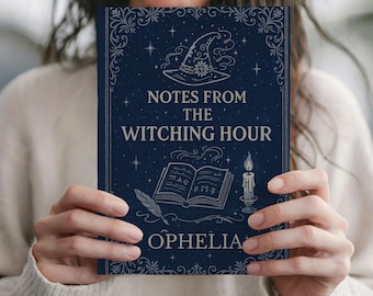 May include: A dark blue notebook with a silver-toned cover design featuring a witch hat, an open book, a candle, and a quill. The text reads "NOTES FROM THE WITCHING HOUR" and "OPHELIA" in a decorative font, surrounded by stars and ornate borders.