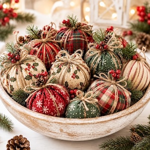 May include: A collection of fabric-covered decorative spheres in a wooden bowl, featuring patterns of red and green plaid, holly leaves, and white snowflakes. Each sphere is accented with twine bows, small pinecones, and clusters of red berries.