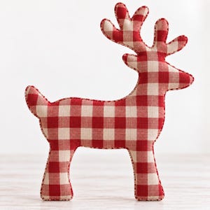May include: A stuffed reindeer ornament featuring a red and white gingham check pattern. The fabric figure has a distinct silhouette with a tall set of antlers, a pointed snout, and a short tail, finished with visible red stitching along the edges.