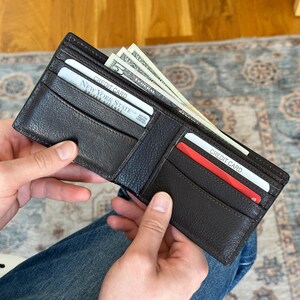 May include: A brown leather wallet open to reveal cash and credit cards. The wallet has two card slots and a cash pocket. The cards are labeled "Credit Card" and "New York State Driver License".