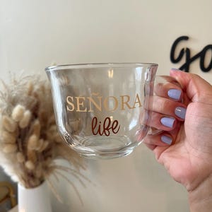May include: A clear glass mug with a gold handle and the text "SEÑORA life" printed on the side.