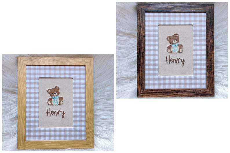 May include: Two framed baby nursery art pieces. One frame is light wood, the other is dark wood. Each features a teddy bear with a blue bow, the name "Henry", and a gingham pattern background. The frames are rectangular.
