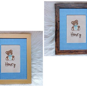 May include: Two framed pictures with a blue and white gingham background. Each frame holds a beige rectangle with a brown teddy bear and the name "Henry" embroidered in brown. One frame is light wood, the other is dark wood.