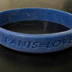 May include: A blue rubber bracelet with the text "PANTS=LOVE" embossed on it.