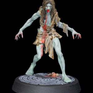 Puede incluir: Figura en miniatura detallada de un zombi con piel azul pálido, ropa hecha jirones y detalles de sangre. La figura se encuentra sobre una base circular con un diseño de adoquines, con un fondo negro. El zombi tiene pelo largo castaño y brazos extendidos.