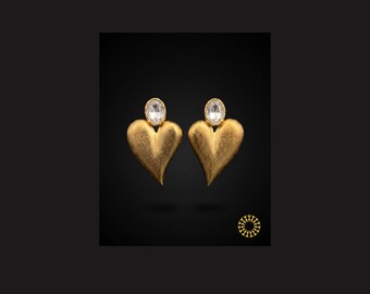 Catch the light and elevate your look with these gold-toned heart-shaped earrings. Each heart is topped with a clear, oval-cut gemstone.