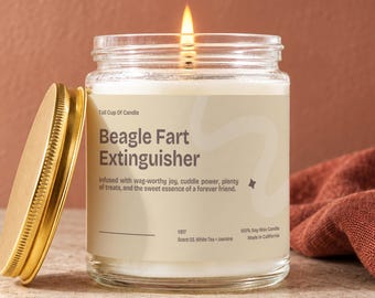 Może przedstawiać: Świeca w przezroczystym szklanym słoiku z zapalonym knotem i złotą metalową pokrywką. Etykieta zawiera napis: Tall Cup Of Candle, Beagle Fart Extinguisher, Infused with wag-worthy joy, cuddle power, plenty of treats, and the sweet essence.