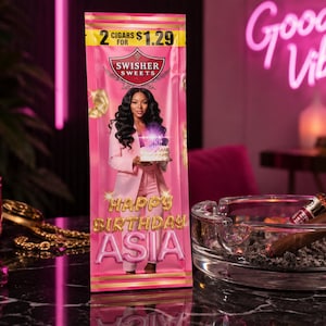May include: A pink Swisher Sweets cigar package with the text "Happy Birthday Asia" and an image of a woman holding a cake. The package also displays "2 Cigars for $1.29". A glass ashtray with a lit cigar is in the foreground.
