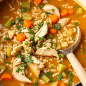 May include: A pot of chicken and rice soup with visible ingredients like carrots, celery, and parsley. The soup has a rich, orange broth and is served with a wooden spoon. A hearty and comforting meal.