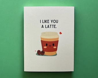 May include: A white card with the text "I like you a latte." and a cartoon illustration of a coffee cup with a smiling face and two coffee beans.