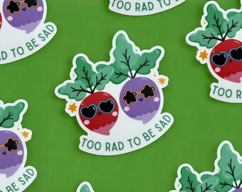 May include: A collection of stickers featuring cartoon radishes with sunglasses and green leafy tops. The radishes are red and purple, with the text "TOO RAD TO BE SAD" in a white, curved font.