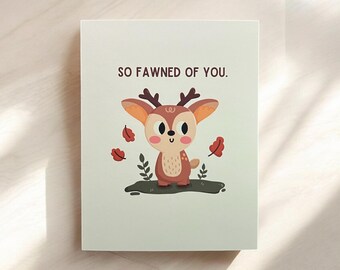 May include: A greeting card with a cute cartoon fawn with brown fur and large eyes. The card has the text "SO FAWNED OF YOU." printed on it.