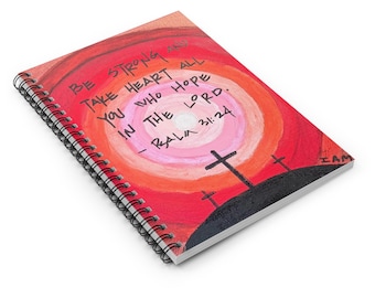 Op de afbeelding: Spiraalgebonden notitieboek met een geschilderde omslag. Het kunstwerk toont een zonsondergangontwerp in rood, oranje en roze, met drie kruisen op een heuvel. De tekst luidt "BE STRONG TAKE HEART ALL YOU WHO HOPE IN THE LORD. - RALA 31:24."