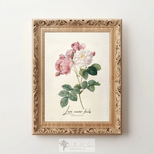 May include: A framed botanical print featuring a cluster of pink and white roses with green leaves. The artwork is set against a cream background and framed in a light brown, ornate wooden frame. The text "Love never fails" is written in black script.