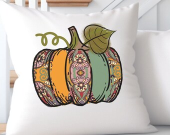 May include: A white throw pillow with a colorful patterned pumpkin design. The pumpkin is orange, green, and brown with intricate details. The pillow is perfect for adding a touch of fall decor to your home.