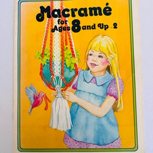 May include: A vintage book cover with a yellow background and the title "Macrame for Ages 8 and Up" in colourful letters. A girl is shown making a macrame plant hanger with a red, white, and green cord. A small red bird is perched on the cord.