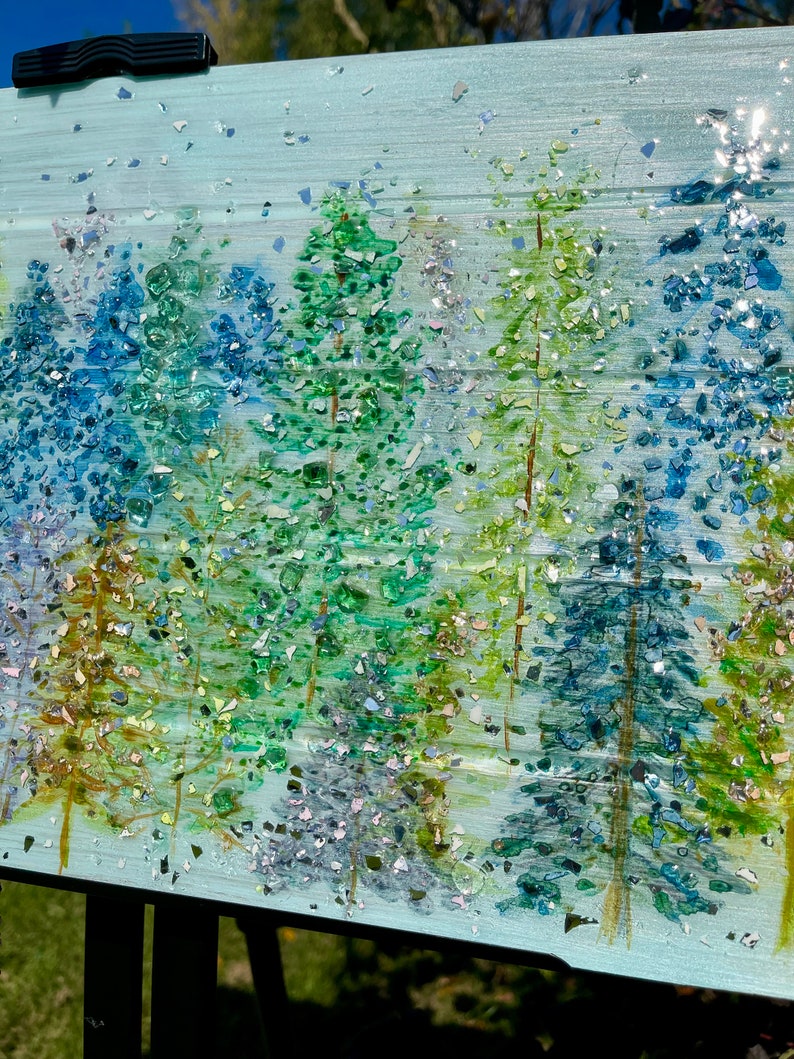 K&ouml;nnte beinhalten: Ein Gem&auml;lde, das eine Waldszene mit B&auml;umen zeigt, die in Blaut&ouml;nen und Gr&uuml;nt&ouml;nen gemalt sind. Der Hintergrund ist hellblau und die B&auml;ume sind mit schimmerndem Glitzer bedeckt.