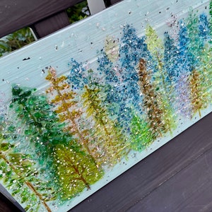 K&ouml;nnte beinhalten: Ein blaues und gr&uuml;nes Mosaik-Kunstwerk, das eine Waldszene darstellt. Die B&auml;ume bestehen aus kleinen Glassplittern und Glitzer, was einen funkelnden Effekt erzeugt. Der Hintergrund ist hellblau, und kleine wei&szlig;e Punkte sind &uuml;ber das gesamte Werk verteilt.