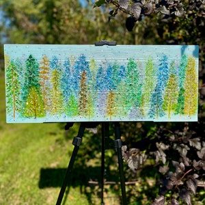 This is a beautiful 28x11 cedar wood board, painted with acrylic paints in the style of a pine forest. There are assorted trees that have a fire glass, crushed glass and glass ice application. The piece is then covered with resin coating.