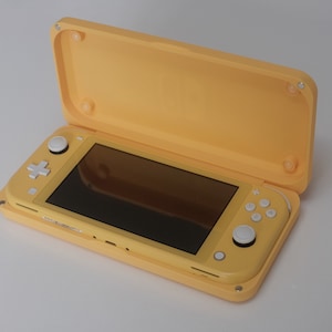 May include: A yellow handheld games console with a matching protective case. The console has a black screen, white buttons, and a directional pad. The case is open, showing the console. The design is sleek and modern.
