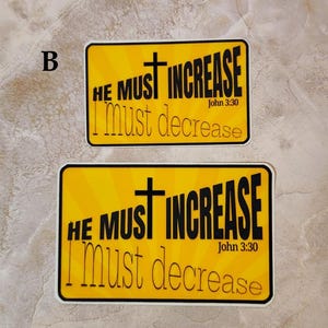 May include: Two yellow stickers with black text and a black cross. The text reads "HE MUST INCREASE I must decrease" and "John 3:30".