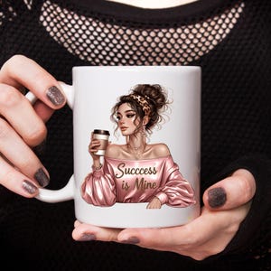 May include: White ceramic coffee mug featuring an illustration of a woman in a pink off-the-shoulder top holding a coffee cup. The text "Success is Mine" is printed on the front. The woman has a leopard print headband.