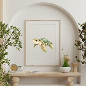 May include: A framed print featuring a watercolor illustration of a sea turtle. The turtle has a green shell, yellow flippers, and a smiling face. The artwork is displayed in a white mat and a light brown wooden frame, suitable for nursery or coastal decor.