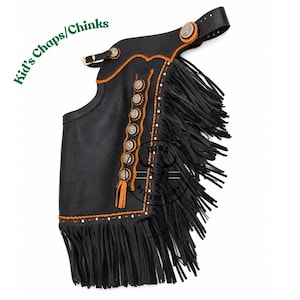 May include: Black leather chaps featuring orange stitching, long black fringe along the side and bottom, and a vertical row of silver-toned decorative conchos. The item includes a buckle strap at the top and displays the text Kid's Chaps/Chinks.