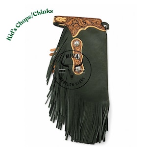 May include: Dark green leather chaps for children featuring long fringe along the side, a tan leather waistband with intricate floral tooling, and three silver-toned decorative conchos. The text Kid's Chaps/Chinks and MIRA WESTERN STORE ESTD 2022 is visible.
