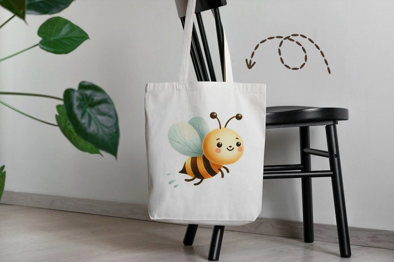 May include: A white tote bag with a cartoon bee design. The bee is yellow and black with a light blue body and a smiling face. The bag has brown handles and is sitting on a black chair.