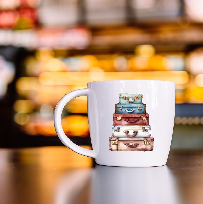 May include: White ceramic mug with a colorful illustration of a stack of vintage suitcases. The suitcases are painted in shades of blue, red, brown, and beige.