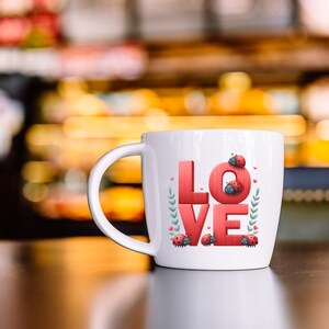Puede incluir: Taza de cer&aacute;mica blanca con un dise&ntilde;o de "LOVE" rojo y mariquitas. La taza tiene un asa y est&aacute; sobre una superficie marr&oacute;n oscura.