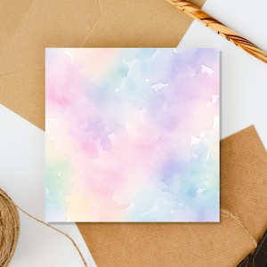 May include: A blank card with a watercolor background in shades of pink, purple, blue, and green. The card is on a white surface with brown paper envelopes and twine.