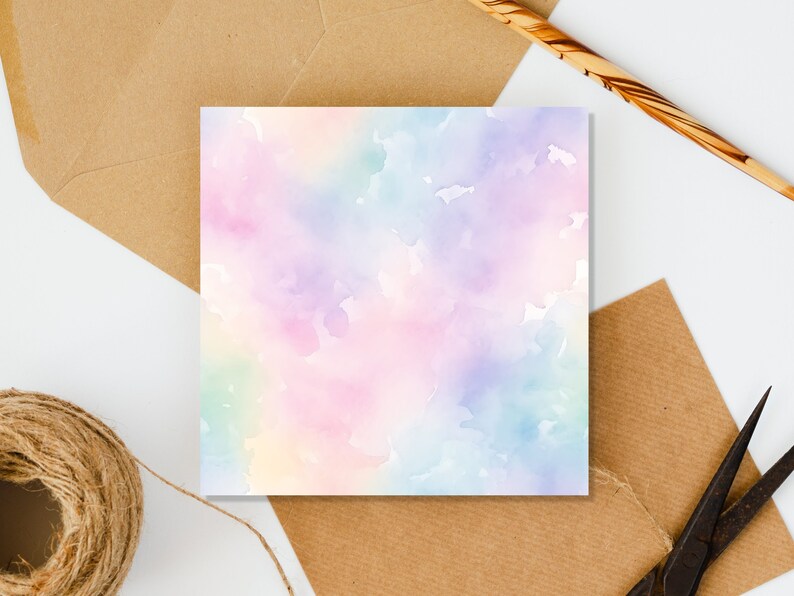 May include: A blank card with a watercolor background in shades of pink, purple, blue, and green. The card is on a white surface with brown paper envelopes and twine.
