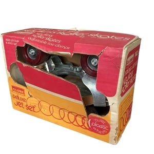 Puede incluir: Caja vintage de patines con ruedas rojas y componentes metálicos plateados. La caja roja y amarilla tiene la inscripción "Roller Skates" y "adjustable toe clamps". También se lee "Deluxe Jet Set" y "Age Group 8 and Up".