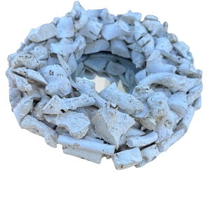 May include: A round mirror with a white, textured frame made of small, irregularly shaped pieces. The frame surrounds a reflective glass surface. The overall design has a rustic, natural aesthetic.