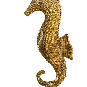 May include: A gold-colored seahorse sculpture made of woven material. The seahorse is a popular nautical decor item.