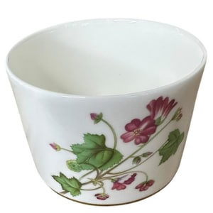 May include: White ceramic bowl with a floral design. The bowl features a botanical pattern of burgundy flowers and green leaves. The flowers are clustered on the side of the bowl, creating a decorative accent. The bowl has a simple, elegant shape.