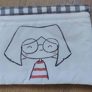 Può includere: Borsa bianca con cerniera con un top in tessuto a quadri bianco e nero. La borsa presenta un disegno a linea nera e bianca di una persona con occhiali e una camicia a righe rosse e bianche.