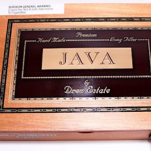 May include: A wooden cigar box with a dark brown and gold framed label. The label reads "JAVA" in gold lettering, with "Hand Made" and "Bong Filler" above. The box is labeled "by Drew Estate". A Surgeon General warning is visible.